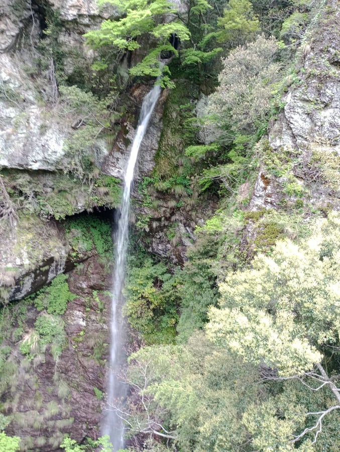 Cascada que cae desde una cueva en la ladera de un acantilado., Japón